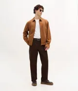 Campera masculina de estilo casual con cuello inglés, cierre frontal por cremallera, bolsillos laterales y ajuste elástico en el bajo. Presenta detalles de recortes en la parte superior delantera.