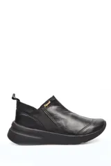 Zapato deportivo negro de cuero liso, con elásticos laterales y suela gruesa.