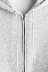 Campera con capucha en felpa de peso medio color gris claro, con interior cepillado suave, cierre y bolsillos delanteros, puños y bajo en punto acanalado. Corte holgado.