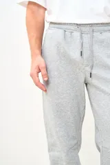 Pantalón de jogging gris melange, con cintura elástica ajustable con cordón, bolsillos laterales y puños ajustados en los tobillos.