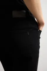 Pantalón slim de denim negro, con tiro medio, corte ajustado y bolsillos clásicos.