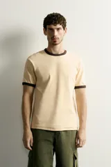 Camiseta regular fit gris melange con cuello redondo y mangas cortas. Presenta acabados con rib en contraste de color marrón oscuro en el cuello y los puños.