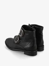 Bota corta marrón de cuero con dos correas con hebillas metálicas en la parte delantera y cierre lateral.