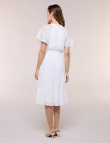 Vestido midi blanco de calce suelto y caída fluida, con escote en V, cuello a la base y apertura abotonada con detalle de puntilla. Cuenta con cintura elastizada con lazo para anudar a tono, mangas cortas con volados y falda con volantes escalonados.