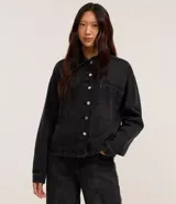 Camisa de jean negra con abotonado delantero, cuello solapa, mangas largas, recortes y bolsillos grandes en el pecho.