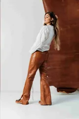 Pantalón de cuero de corte recto y tiro medio, color verde oscuro, con diseño artesanal y botón frontal.