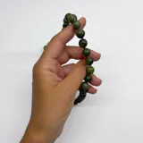 Collar de cuentas esféricas de jade verde, con separadores de hilo lila y cierre de mosquetón dorado.