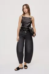 Jean de tiro medio y corte barrel con pierna amplia y ligeramente curva, estilo de cinco bolsillos en denim negro lavado.