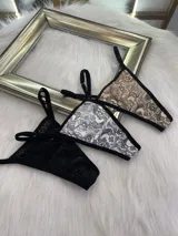 Pack de tres microtangas de encaje con diseño floral, cuentan con tiras laterales regulables y bordes con terminación en cinta elástica. El set incluye una prenda negra, una blanca con estampado floral negro y una beige con estampado floral negro.