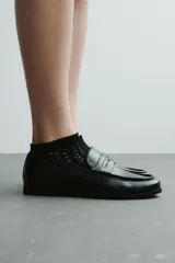 Mocasines estilo penny de color negro, con costura tradicional en la parte delantera y suela baja.