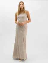 Vestido largo de encaje color beige, con escote recto decorado con pedrería y perlas, tirantes anchos y tajo lateral en la falda.