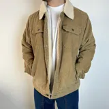 Chaqueta de pana color beige con cuello y forro de corderito blanco, cierre con botones y bolsillos frontales.