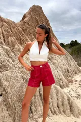 Top corto blanco con escote halter y tiras finas en la espalda.