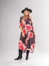 Vestido camisero largo con estampado floral en tonos rojos y negros, con cuello camisero, abotonadura frontal y mangas largas con puños abotonados.