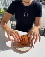 Anillo plateado con forma orgánica irregular y un agujero en el centro.