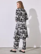 Cardigan largo de satén plisado con estampado abstracto en blanco y negro, marca Cyrus. Presenta aberturas laterales.