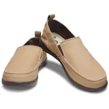 Mocasín Crocs modelo Walu Syn de estilo náutico, confeccionado en lona azul con detalles en color marrón. Presenta suela de material Croslite flexible y diseño slip-on con ojales decorativos laterales.