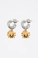 Par de aros tipo argolla de metal plateado con dije colgante de mariquita dorada con detalles negros esmaltados.