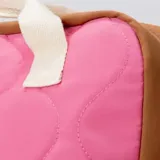 Mochila con diseño capitoneado y bloques de color en rosado, azul, beige, marrón y amarillo. Cuenta con un compartimento principal con cierre, un bolsillo frontal con solapa y cierre, y asas superiores de mano además de las correas de hombro.
