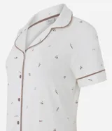 Camisón corto color blanco marfil con estampa floral sutil, cuello solapa, mangas cortas y cierre frontal con botones. Cuenta con ribetes en contraste en cuello y puños.