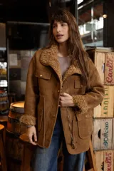 Campera de efecto gamuza color tostado con interior de corderito sintético. Presenta cierre frontal, bolsillos delanteros con solapa, cintura ajustable con cordón y puños con detalle de corderito.