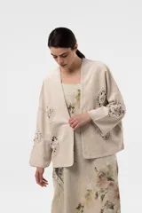 Chaqueta de gamuza color beige, con calce amplio y relajado, mangas anchas y detalles de inserciones de crochet con motivos florales.