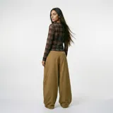 Pantalón de corte amplio y holgado, color mostaza, con diseño de tiro alto y costuras horizontales en la parte inferior de las piernas.