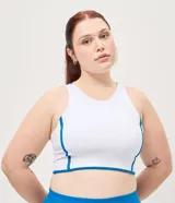 Top deportivo femenino confeccionado en microfibra, de color blanco con vivos en azul, escote redondo, copa y breteles anchos.