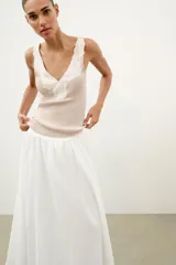 Top de punto canalé en color beige, con escote en pico adornado con una delicada aplicación de encaje blanco y tirantes anchos.