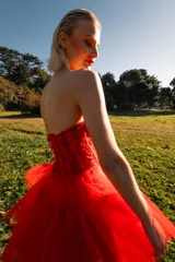 Vestido de fiesta rojo de tul con corpiño strapless de encaje y falda asimétrica de varias capas.