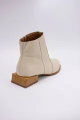 Botín de cuero dorado con punta fina y taco bajo cuadrado de madera.