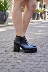 Botinetas de cuero negro con taco ancho, plataforma delantera y diseño con boca en V en el tobillo.