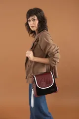 Cartera bandolera de cuero color marrón con textura croco en la solapa y cuero liso negro en el cuerpo. Tiene correa regulable y extraíble, bolsillo trasero con cierre y forro interior de tela.