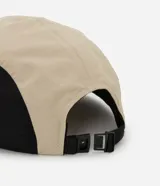 Gorra tipo 5 panel confeccionada en microfibra de poliamida, con diseño de bloques de colores en beige, negro y verde oliva. Presenta visera recta, cierre posterior ajustable y etiqueta frontal con gráfico y frase Stay Grounded.