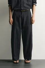 Pantalón chino para hombre confeccionado en denim ligero de mezcla de algodón y lino, sin lavados. Presenta un corte relajado con tiro medio, bolsillos frontales, bolsillos traseros y cierre frontal con cremallera y botón.