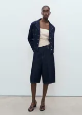 Short de jean de tiro medio con diseño recto, confeccionado en algodón estilo tejano vaquero. Cuenta con cuatro bolsillos y cierre oculto de botón, gancho y cremallera.