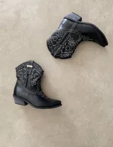 Bota corta estilo western de cuero color marrón, con taco cuadrado de 5 cm y diseño clásico. Presenta un acabado desgastado en la puntera y el talón.