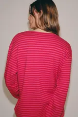 Remera de manga larga con diseño de rayas horizontales en tonos fucsia y rosado, cuello redondo y corte holgado.