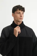 Campera con cierre frontal, cuello alto y bolsillos laterales con detalle de cinta. Confeccionada en sherpa doble faz combinada con nylon de alta calidad y cierres engomados.