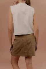 Minifalda de gabardina color tostado, de tiro medio con bolsillos delanteros y traseros, presillas para cinto y cierre frontal con botón metálico.
