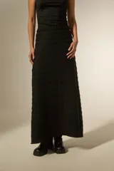 Pollera larga de corte recto y cintura elástica, confeccionada en tejido negro con textura de franjas horizontales.