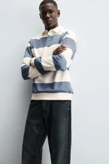 Sudadera de manga larga estilo polo con diseño de rayas horizontales anchas en azul marino y blanco. Presenta cuello de solapa en contraste, cierre frontal con botones ocultos y acabados en rib en puños y bajo.