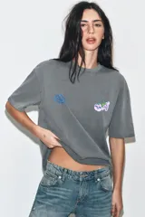 Camiseta de algodón con efecto lavado, corte oversize, cuello redondo y manga corta. Presenta estampados gráficos en el frente.