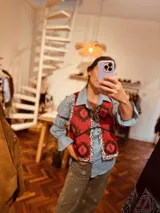 Chaleco rojo con estampado geométrico en blanco y negro, con ribetes negros y ajuste con lazos laterales.