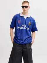 Camiseta de estilo polo con cuello camisero, manga corta y calce relajado. Presenta un diseño en color azul con estampado frontal "FIFA WORLD CUP" y detalles gráficos en contraste. Confeccionada en tejido técnico de poliéster reciclado.
