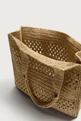 Bolso tipo shopper de color naranja con acabado trenzado y diseño estructurado. Cuenta con compartimento principal y dos asas cortas de mano.