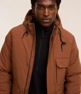 Campera tipo parka color marrón, con capucha ajustable, cierre frontal de cremallera y botones, y múltiples bolsillos con solapa en el frente. Presenta puños ajustables con botones y un diseño funcional de estilo urbano.