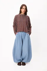 Pantalón de denim estilo palazzo con silueta holgada y diseño de pinzas en la cintura. Presenta un corte amplio y fluido, con cierre frontal y bolsillos laterales.