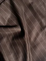 Pantalón sastrero de vestir color chocolate con finas rayas verticales blancas, de tiro alto y corte recto. Cuenta con bolsillos laterales y pretina trasera elastizada.