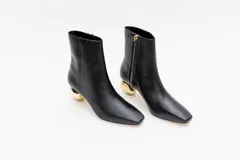 Botas cortas de cuero negro con punta fina y cierre lateral. Taco dorado con forma de esfera.